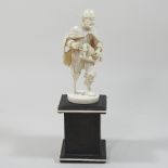 A 19th century French Dieppe carved ivory figure, of a busker, playing a hurdy gurdy,