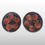 A near pair of Moorcroft Pomegranate pattern chargers, on a mottled blue ground,