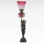 A 19th century bronzed spelter and brass figural oil lamp, modelled as a water carrier,