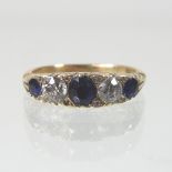 An early 20th century 18 carat gold sapphire and diamond five stone ring, with textured shoulders,