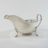 An early 20th century silver sauce boat, of helmet shape, with a plain handle, on three hoof feet,