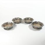 A set of four silver plated wine coasters, each of scrolled design, with a turned wooden base,
