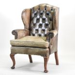A Victorian leather upholstered studded button back wing armchair, on cabriole legs and pad feet,