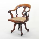 A Victorian swivel desk chair, with a cane seat, on a splayed base,