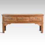 An 18th century pitch pine dresser base, with a plank top, containing three short drawers,