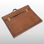 An early 20th century brown leather folio case, with a leather strap handle and brass buckles,