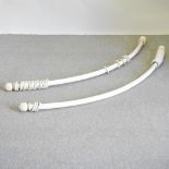 A pair of curved white painted curtain poles,