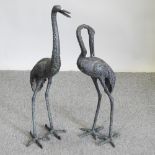 A metal garden model of a crane, together with another,