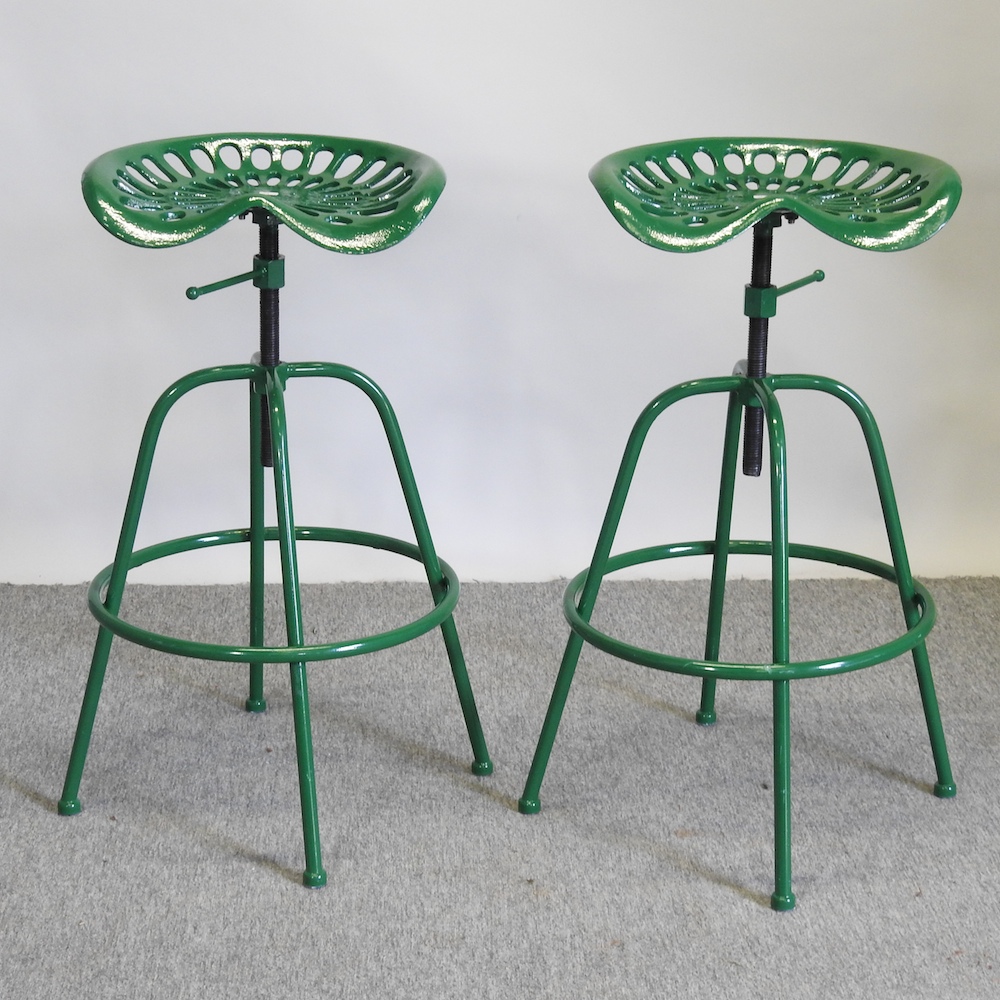 A pair of green painted metal revolving tractor seat bar stools