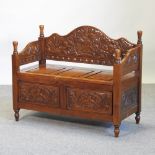 An early 20th century carved hardwood settle, with a rising seat,