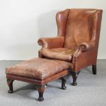 A brown leather upholstered wing armchair, together with a footstool,