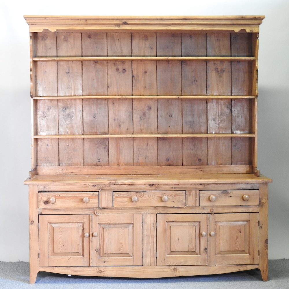 A pine dresser, the plate rack above drawers and cupboards,