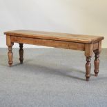 A rustic pine bench, on turned legs,