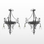 A pair of antique black painted wrought iron three branch chandeliers, with glass shades,