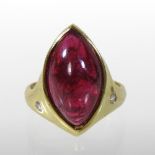 An 18 carat gold, polished ruby coloured and diamond ring, set with an elliptical uncut stone,