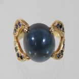 An unmarked modern sapphire dress ring, having a large central cabochon,