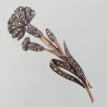 An unmarked diamond brooch, in the form a flower, with diamond set petals and leaves,