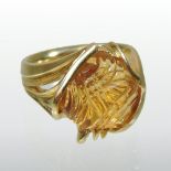 A modern 18 carat gold carved topaz ring, of natural shape, in a scrolled asymmetrical setting,