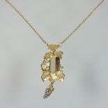 A modern 18 carat gold necklace, set with a baguette cut quartz, with a vine leaf surround,