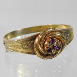 An ornate unmarked gilt bangle, of hinged design, finely engraved with scrolling foliate designs,