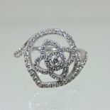 A De Beers 18 carat gold diamond cluster ring, line set with an asymmetrical flower head,
