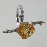 An 18 carat gold carved yellow topaz and diamond ring, of rose and thorn design,