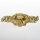 An ornate gilt stomacher, inset with a central oval citrine, within a profusely scrolled surround,
