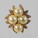 An 18 carat gold pearl and diamond cluster ring, set with four central pearls,