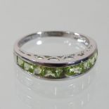 A modern 18 carat gold and peridot half hoop eternity ring, size N/O, 3.