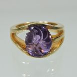 A modern 18 carat gold single stone amethyst ring, the stone carved as the head of a lady,