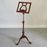An adjustable mahogany music stand, on a tripod base,