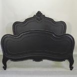 A black painted carved wooden French bedstead, with a slatted wooden base,