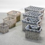A set of three wicker baskets, together with a set of four wicker baskets, with grey fabric liners,