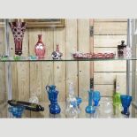Two shelves of various coloured glass items