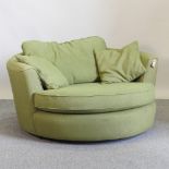 A modern green upholstered swivel sofa, with loose cushions,