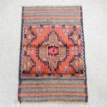 A woollen rug, with geometric designs on a red ground,