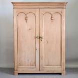 An antique pine double wardrobe, on a plinth base,