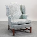 A green damask style upholstered wing armchair,