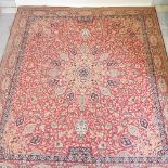 A late 20th century Persian woollen carpet, with all over floral design, on a red ground,