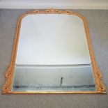 A large bevelled glass gilt framed wall mirror, of arched shape,