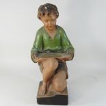 A painted plaster shop display model of a young boy seated,