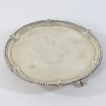 A George III silver waiter, of circular shape, with a piecrust edge, on ball and claw feet,