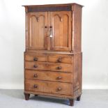 An early 19th century oak and mahogany cabinet, enclosed by a pair of panelled doors.