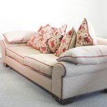 A beige upholstered sofa, 254cm, with loose cushions, together with a set of three long curtains,