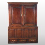An 18th century and later oak cupboard, enclosed by a pair of panelled doors, with drawers below,