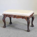 A striped upholstered footstool seat, on claw and ball feet,