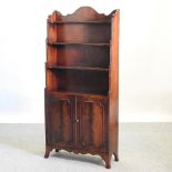 A reproduction mahogany waterfall bookcase, with cupboards below, on swept bracket feet,