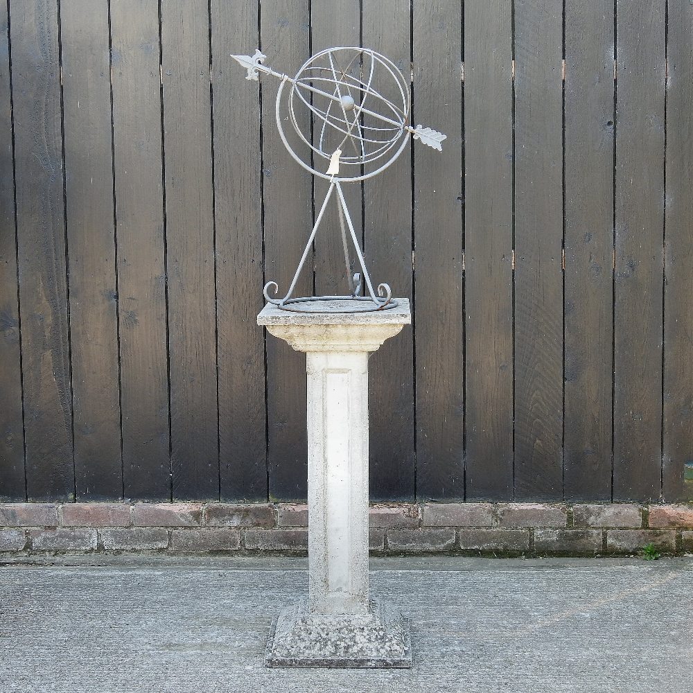 An iron garden armillary sphere, mounted on a reconstituted stone column,