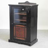 An Edwardian amboyna and ebonised music cabinet, with a glazed door,