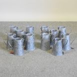 A set of twelve modern galvanized jugs, with embossed decoration,